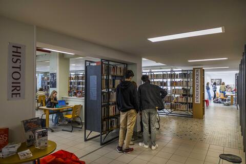 Groupe d'étudiants devant un rayonnage de la bibliothèque