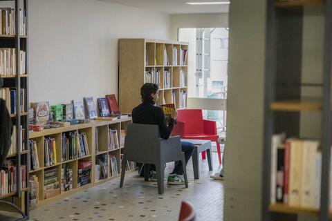 Un étudiant est assis et lit dans la section bandes dessinées et jeux