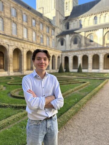 Baptiste Beker, plume et conseiller municipal pour les éléments de language de la ville de Caen, se tient debout dans la cour intérieure de l'Hôtel de Ville de Caen.