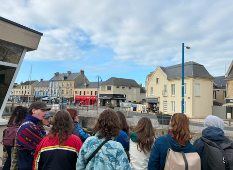 Les étudiantes et étudiants sont de dos en train d'observer l'écluse du port. Au fond : des bâtiments et des commerces.