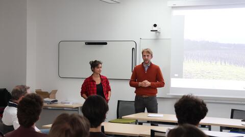 Nora Houguenade à gauche et Nicolas Escach à droite sont en train d'échanger avec les étudiantes et étudiants en face que l'on peut voir de dos. Au fond, nous apercevons la vidéo-projection du film sur un grand tableau blanc. 
