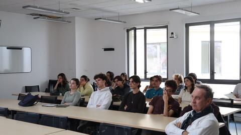 Assis devant leurs tables sur plusieurs rangées, les étudiantes et étudiants se concentrent sur le film qu'ils regardent. 